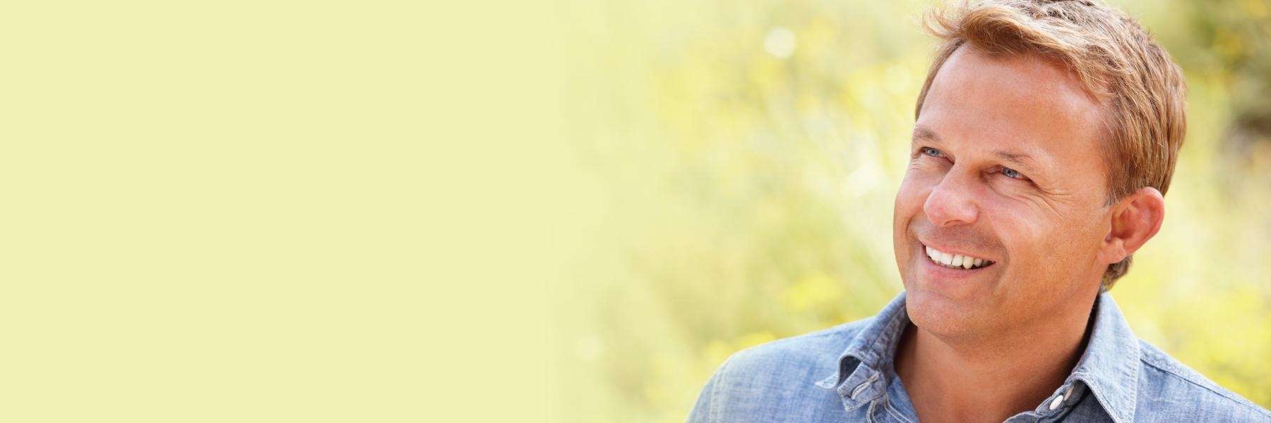 A smiling man standing in tall grass | implant supported dentures fl