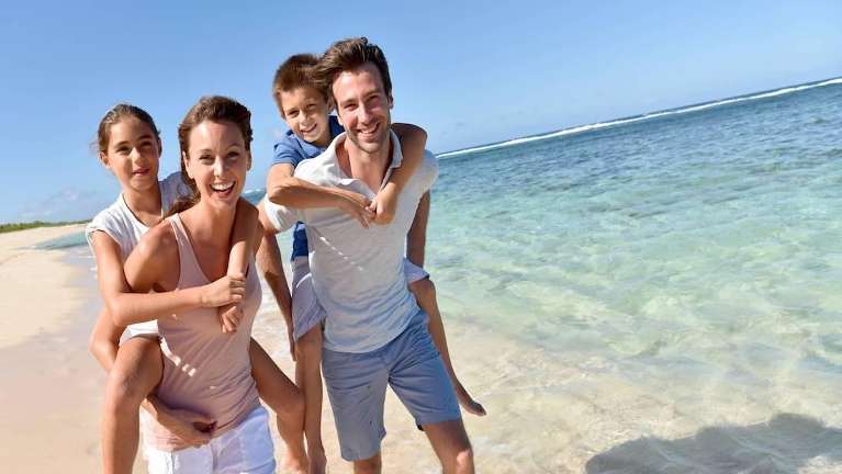 A smiling family at the beach | dentist St Augustine