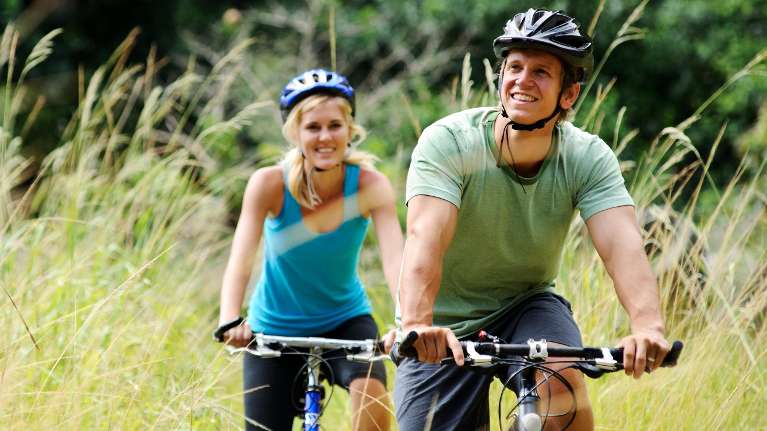 A man and woman riding their bikes in nature | missing teeth st augustine