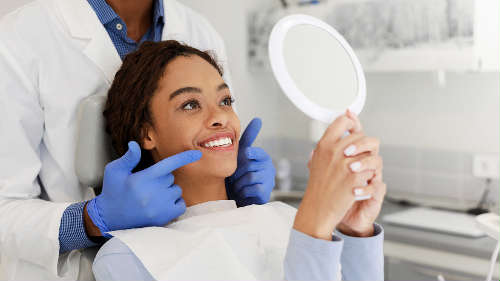 A woman smiling and looking at the mirror after getting Tooth-Colored Fillings in St. Augustine, FL